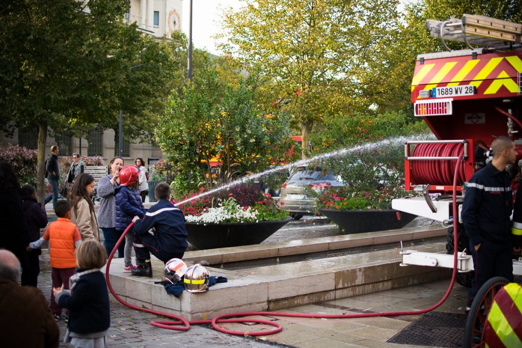 Firemen showing a little kid how to use the hose